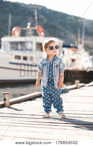 Trendy baby girl 2-3 year old wearing denim clothes outdoors. Looking at camera. Summer time.