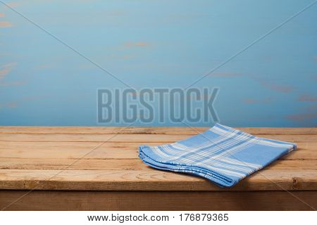 Empty wooden table with checked blue tablecloth over rustic painted wall with copy space