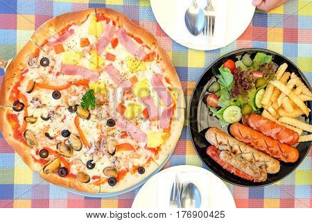 Sausage fried and pizza hawaiian with vegetables on chintz.