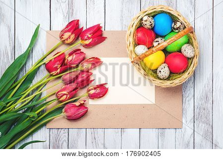Easter eggsbeautiful red tulips blank note on the wooden background.