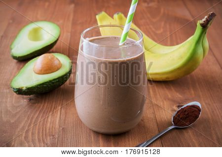Healthy chocolate avocado banana smoothie on wooden background