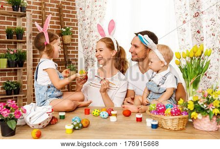 Happy easter! family mother father and children having fun paint and decorate eggs for holiday