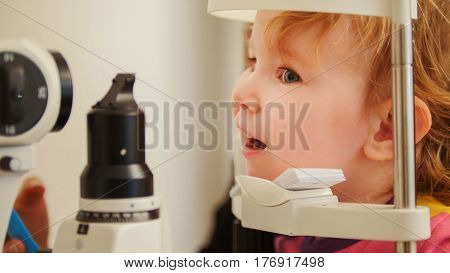 Little girl in ophthalmological clinic checks eyesight, telephoto