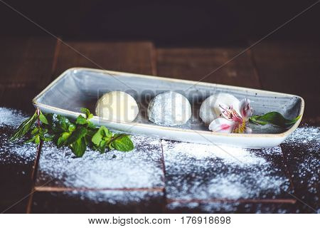 Mochi dessert in plate with flower on wood table