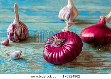 Red onions garlic on a blue wooden table close up