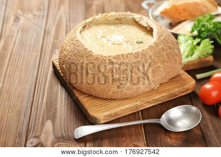Delicious cream soup in bread on table