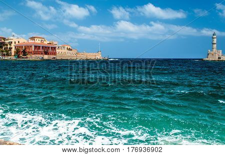 The port of a small Mediterranean town, old stone lighthouse.Azure sea, blue sky.