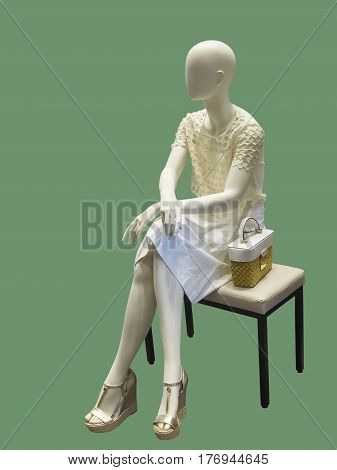 Sitting female mannequin against green background. No brand names or copyright objects.