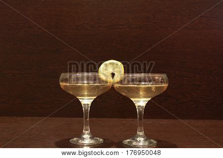 Two glasses of wine and lemon on a dark table