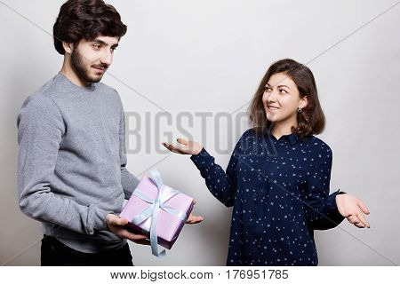 Man giving a present to his girlfriend. Romantic surprise woman receives a gift from her boyfriend. Woman in love surprised looking at her boyfriend who gives her a present.