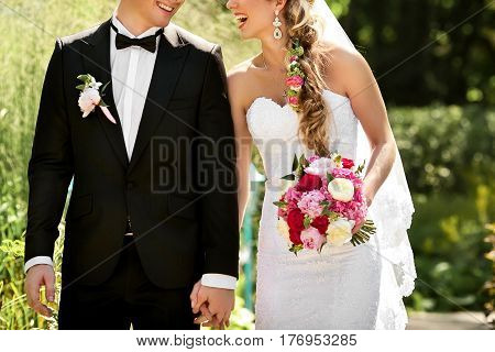 Young wedding couple hold each other on by hands and walking in park