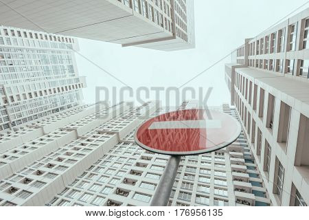 View from bottom of modern contemporary white skyscraper apartment building with regular windows and balconies on a bright day with a red stop road sign reflecting the building Moscow Russia