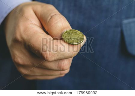 Business man in blue suit holds golden euro cent on hand fingers tossing coin heads or tails game