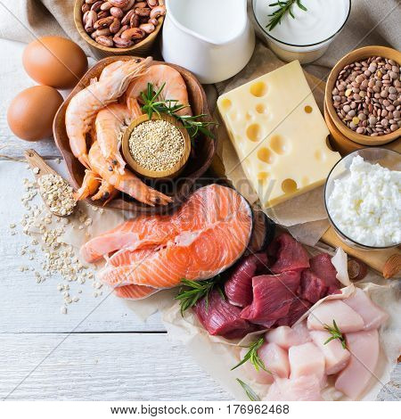 Assortment of healthy protein source and body building food. Meat beef salmon shrimp chicken eggs dairy products milk cheese yogurt beans quinoa nuts oat meal. Top view