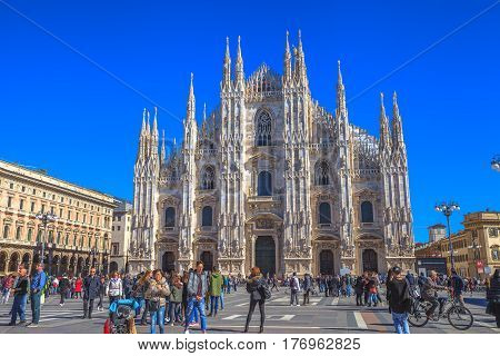 MILAN, ITALY- MARCH 7, 2017: Gothic cathedral facade in Piazza Duomo square of Famous Milan Dome Cathedral. Tourists walking and taking pictures in fashion capital Milano.