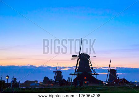 Sunset in landscape with mill the Netherlands. Silhouettes of Dutch mills near the lake at sunset in a rural landscape. Dutch mill by evening. Dutch mill by evening.