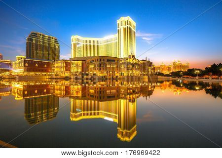 Scenic panorama cityscape of Macau, China, reflected on lake at sunset. Urban night scene.