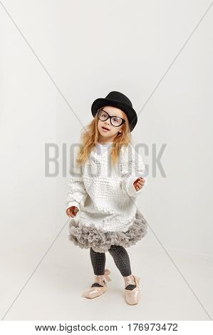 Cute little girl hipster ballerina in a ballet tutu pointes glasses and a hat. The younger generation of dancers.