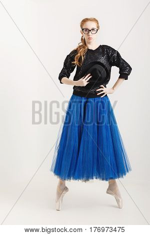 Sweet ballerina hipster in a ballet tutu pointes and glasses dances with a hat. Modern dance.