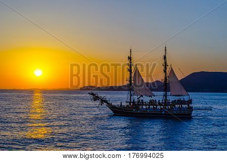 Two-masted sailing ship on the background of the setting sun.