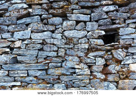 Stone Wall of rural Building made with manual work without linking solution of small pieces of rocks carefully tailored to each other with small empty Window.