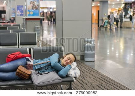 Young Woman Sleeping At The Airport While Waiting For Her Flight. Tired Female Traveler Sleeping On 