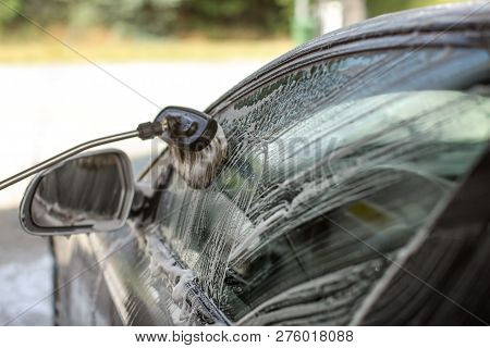 Side Of A Car Washed In Self Serve Carwash. Brush Cleaning Glass, Strokes Visible In Shampoo Foam.