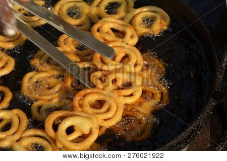 Close Up Of  Golden Color Jalebi Being Soaked In Sugar Syrup By Hand Using A Fork In Daylight In The