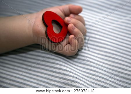 The Newborn Holds The Red Heart In His Hand. Congratulations To The Holiday