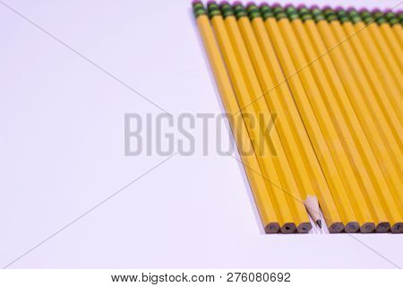 Angle Of Sharpened Pencil In Line Of Unsharpened Pencils On White Background With Copy Space