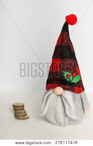 Scandinavian Swedish Gnome In Gray Clothes And A Plaid Hat With Wood On A White Background