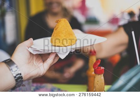 Person Holding A Plate With A Coxinha (brazilian Chicken Croquette) On It
