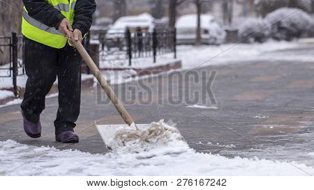 Man With Snow Shovel Cleans Sidewalks In Winter.