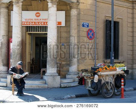 Nicosia, Cyprus - March 17, 2018: A Man Selling Fruit From A Stall On A Cart Sits On The Pavement In