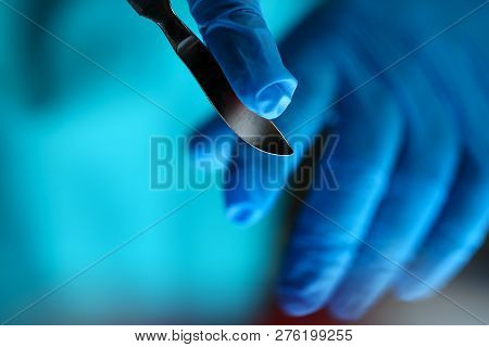 Surgeon Arms In Sterile Uniform Holding Sharp Knife While Operating Patient In Surgical Theatre Clos