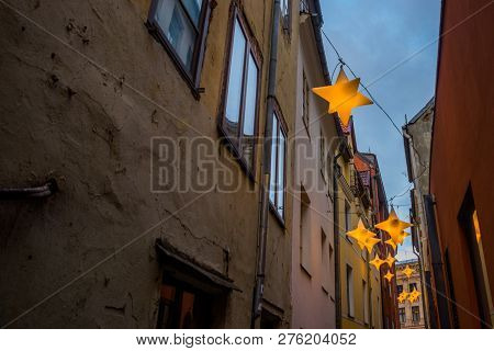 Narrow Rozena Street In Old Town Riga, Latvia With Stars Garland. Christmas Decoration On The Europe