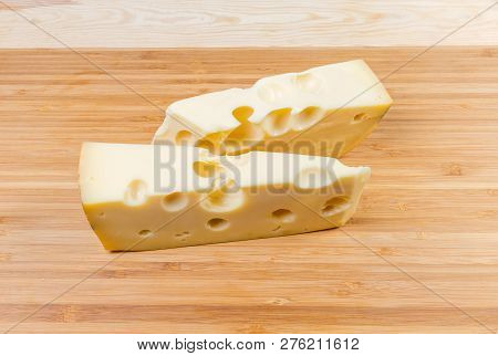 Two Pieces Of Swiss-type Cheese On Wooden Cutting Board