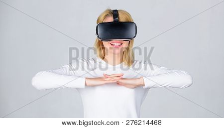 Portrait Of An Amazed Girl Using A Virtual Reality Headset Isolated On Grey Background. Woman Using 