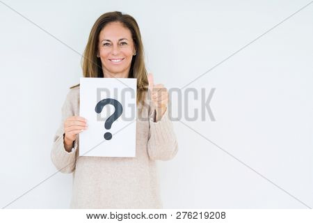 Middle age woman thinking and holding paper with question mark symbol over isolated background happy with big smile doing ok sign, thumb up with fingers, excellent sign
