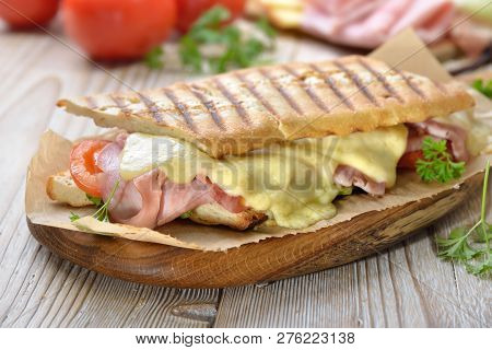 Grilled And Pressed Toast With Smoked Ham, Cheese, Tomato And Lettuce Served On Sandwich Paper On A 