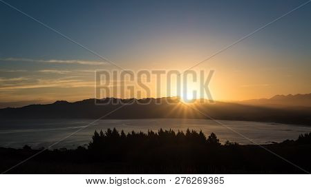 A Brand New Day As The Sun Rises Above The Mountain. Below Are Ocean And Tree Line. This Image Is So