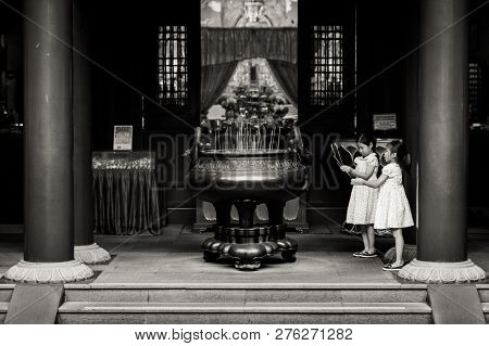Singapore - May 2012: A Pair Of Unidentified Children Praying For Good Luck. Incense Is Burning In P