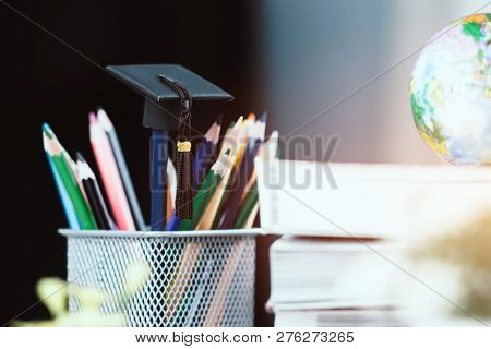 Education Graduate Study Concept: Black Graduation Hat On Pencils, Blur Of Europe Earth World Globe