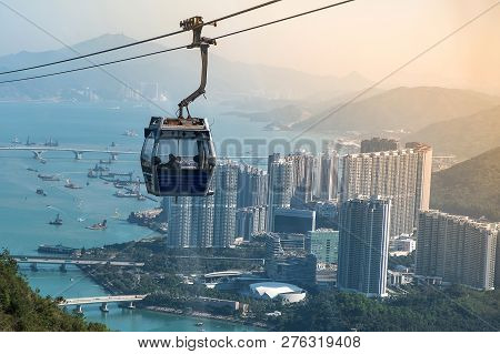 Ngong Ping Cable Car With Tourists Over Harbor, Mountains And City Background, To Visit The Tian Tan