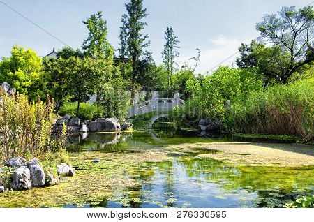 An Arched Bridge Over A  Manmade Pond Within The Luzhi Ancient Town Scenic Area In Wuzhong China In 
