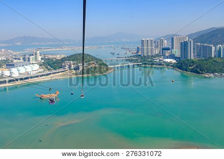 Ngong Ping Cable Car With Tourists Over Harbor, Mountains And City Background, To Visit The Tian Tan
