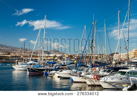 Panoramic View Of Boats And Yachts At Dockside On Background Of Hilly Shore And Cloudy Blue Sky