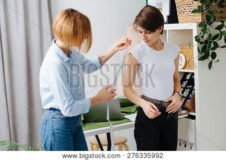 Young Female Fashion Designer Taking Measurements Of A Woman To Design New Clothes. They Both Have S