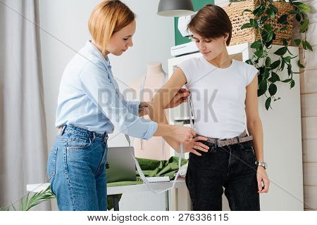 Young Female Fashion Designer Taking Measurements Of A Woman To Design New Clothes. They Both Have S
