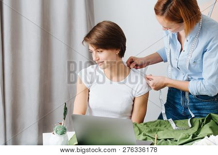 Young Female Fashion Designer Taking Measurements Of A Woman To Design New Clothes. They Both Have S